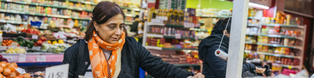 Lady picking up and looking a fruit at a market